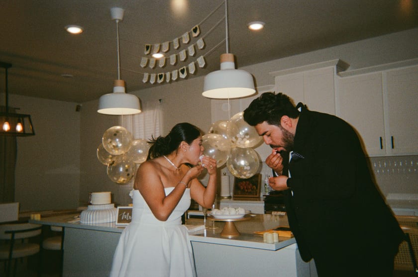 Film photo: leaning in close over the cake at the kitchen counter