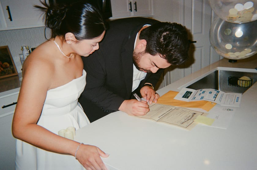 Film photo: both leaning over the counter to sign the license