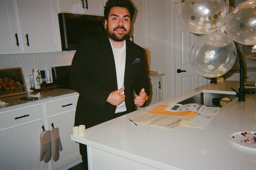 Film photo: Chris mid-story at the counter, champagne balloons floating behind