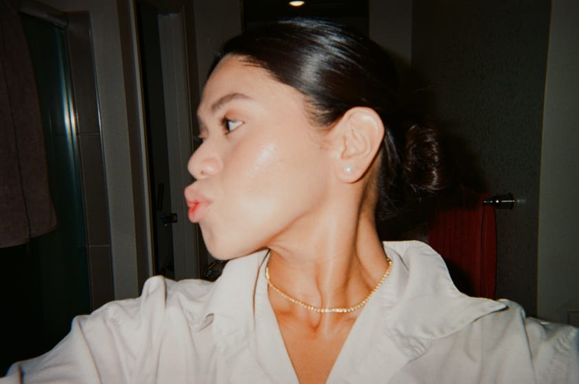 Film photo: Ann, hair pinned, blowing a kiss while getting ready