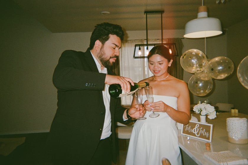 Film photo: pouring the first glasses as husband and wife