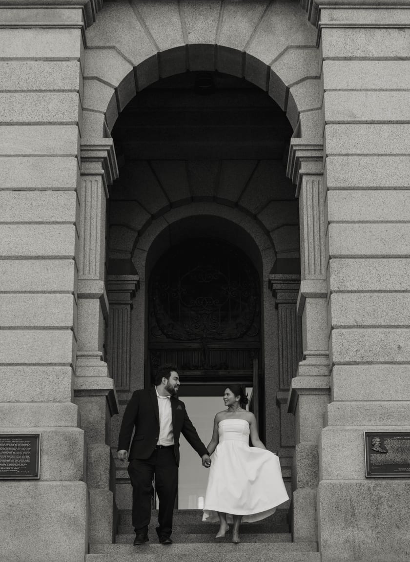 Black-and-white: the couple walks out through the Capitol's grand arched entrance holding hands