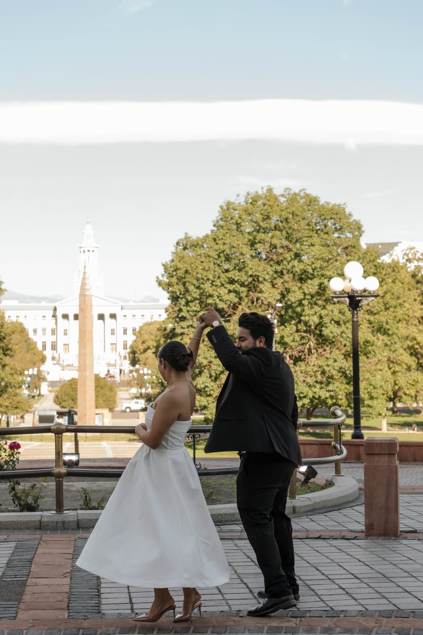 Chris twirls Ann on the terrace above Civic Center Park at golden hour