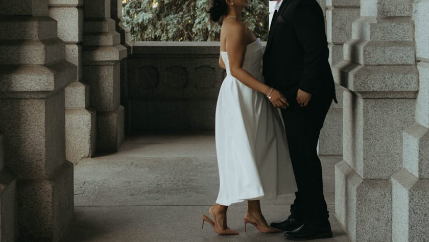 Standing close in the colonnade, hands nearly touching
