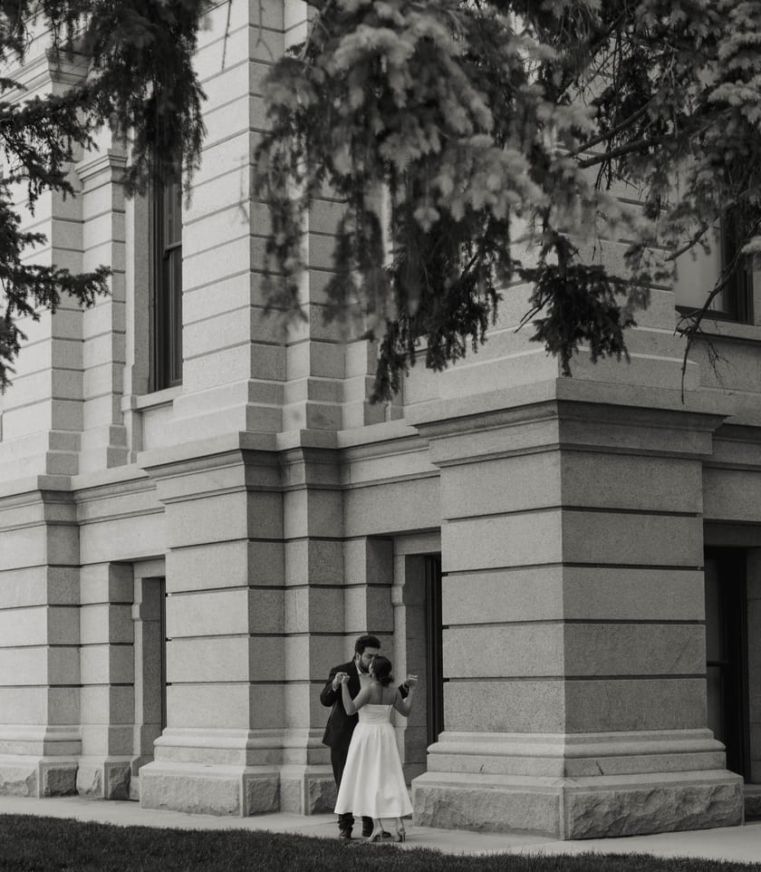 Black-and-white: a small kiss beside the vast granite corner of the Capitol