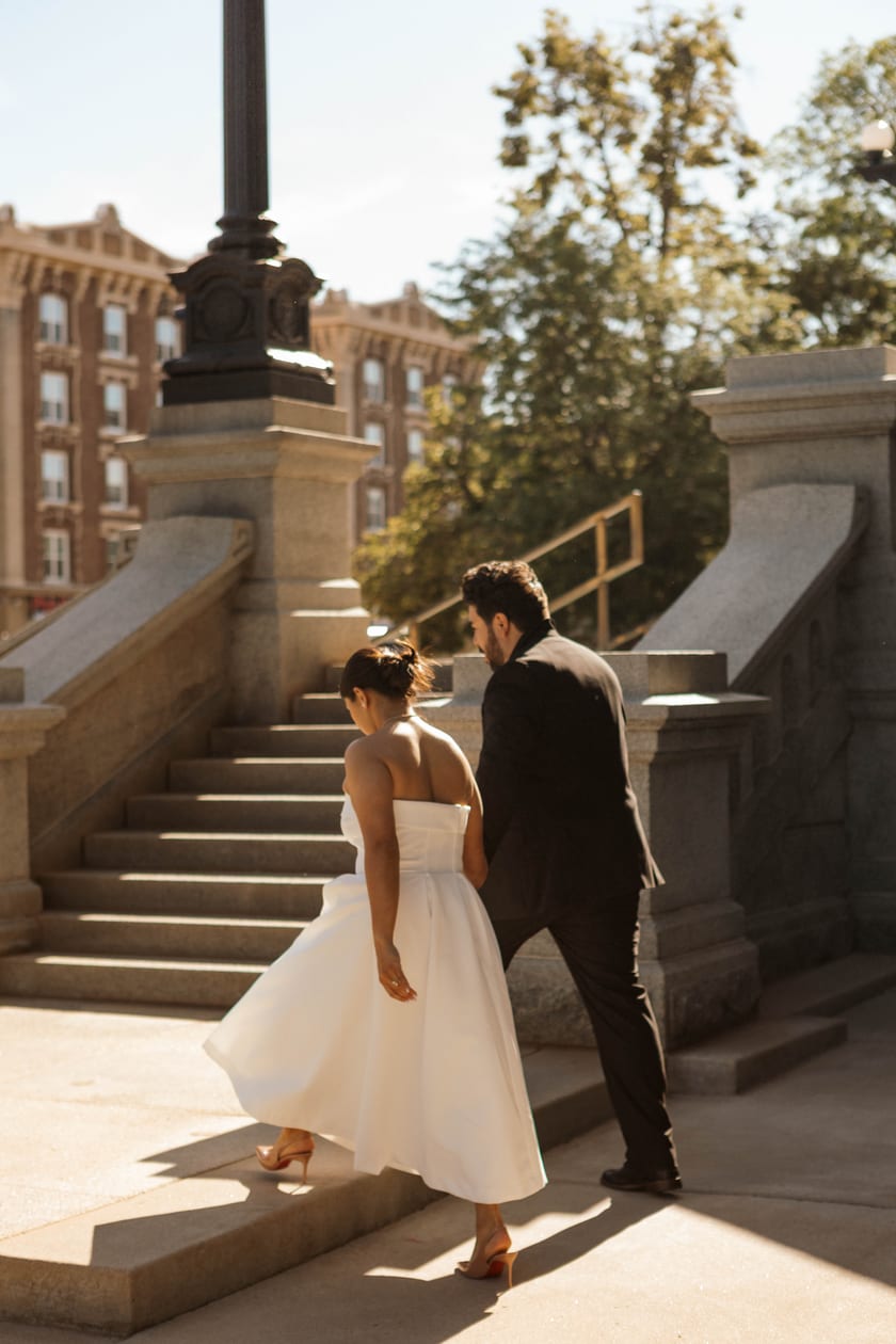Climbing the sunlit side steps, dress catching the light