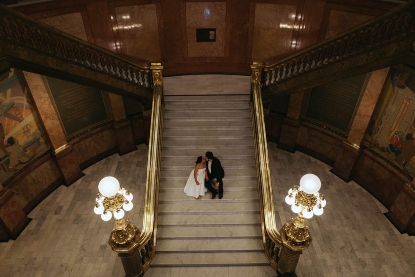 The marble stair hall of the Capitol, murals and brass lamps aglow