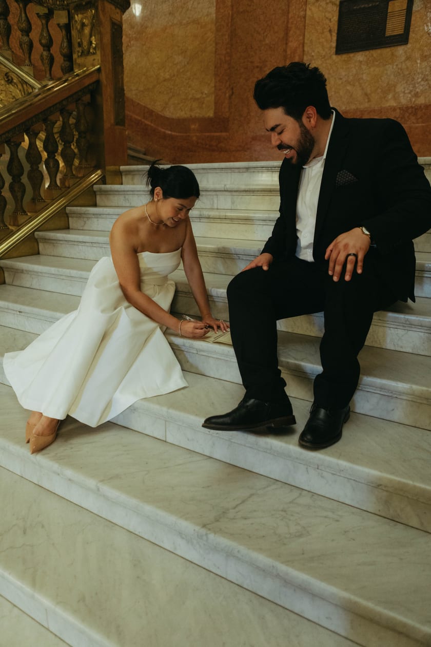 Ann fixes her shoe while Chris waits on the marble steps
